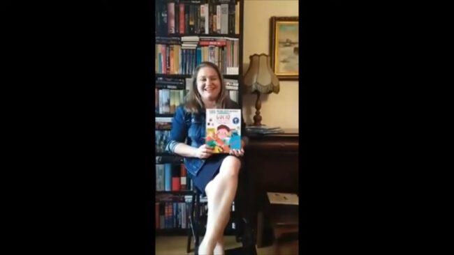 uśmiechnięta bibliotekarka pokazuje omawianą książkę
