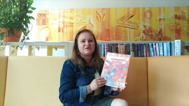 uśmiechnięta bibliotekarka pokazuje omawianą książkę