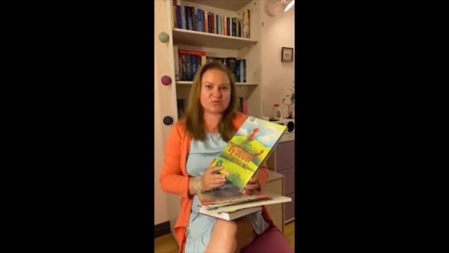 uśmiechnięta bibliotekarka pokazuje omawianą książkę
