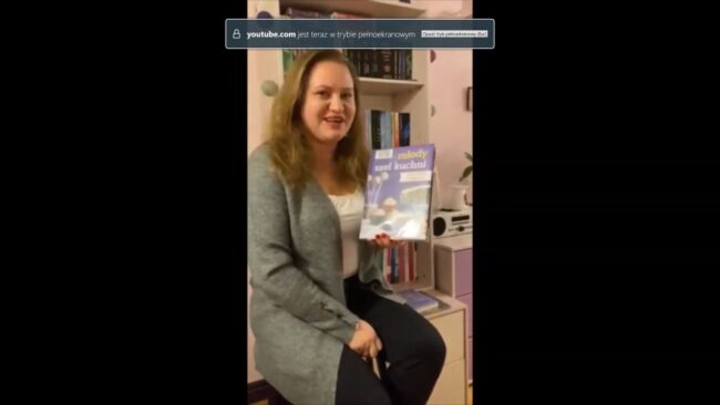 uśmiechnięta bibliotekarka pokazuje omawianą książkę