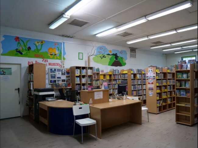 sala biblioteczna - stoisko bibliotekarzy, na ścianach malunki dla dzieci, m.in. pszczółka Maja