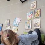 zdjęcie przedstawia dzieci siedzące na podłodze przy książkach w trakcie zajęć bibliotecznych