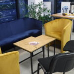 Na zdjęciu widoczne są dwa żółte fotele, granatowa sofa, stolik i krzesło,.