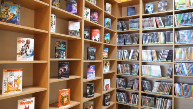 na półkach regałów pudełka z filmami na dvd