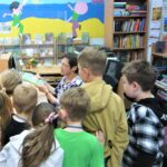 bibliotekarka pokazuje dzieciom, jak się wypożycza książki