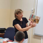 bibliotekarka czyta i pokazuje książkę uczniom podczas warsztatów