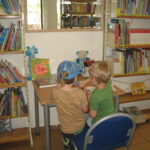 chłopcy przy stoliku przeglądaj książki biblioteczne
