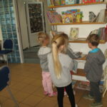dzieci przeglądają książki w regale