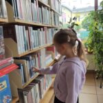 dziewczynka przegląda książki w bibliotece