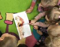 dzieci słuchają czytanej książki i oglądają ilustracje