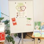 tablica magnetyczna, a na niej plakat promujący projekt Ekobiblioteka; obok tematyczna wystawka książek o ekologii i pojemnik na zużyte baterie