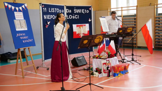 artyści z Pro Arte śpiewają i tańczą na scenie; w tle napis 11 listopada, święto niepodległości