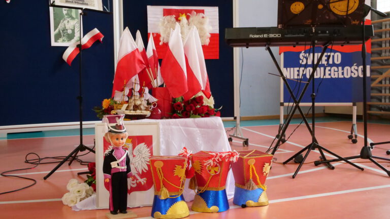 wystawka na scsenie: flagi Polski, figurka ułana, godło Polski