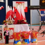 wystawka na scsenie: flagi Polski, figurka ułana, godło Polski
