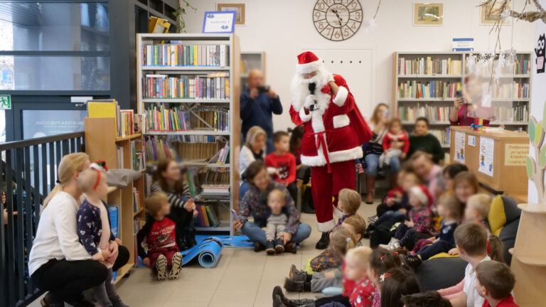 Święty Mikołaj przechodzi przez bibliotekę pośród szczęśliwych dzieci