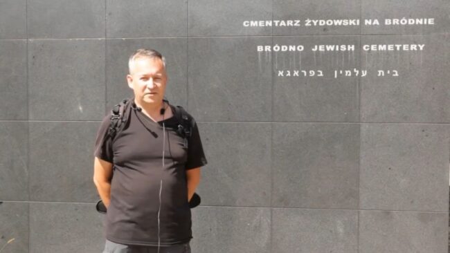 Krzysztof Gajda stoi przy murach cmentarza żydowskiego na Bródnie