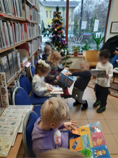 przedszkolaki zwiedzają bibliotekę i oglądają książeczki