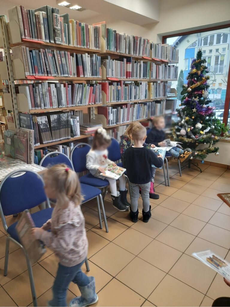 przedszkolaki zwiedzają bibliotekę i oglądają książeczki