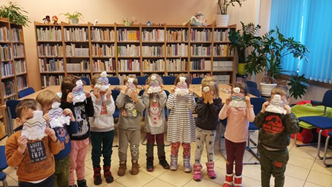 dzieci prezentują prace plastyczne - papierowe czapki zimowe