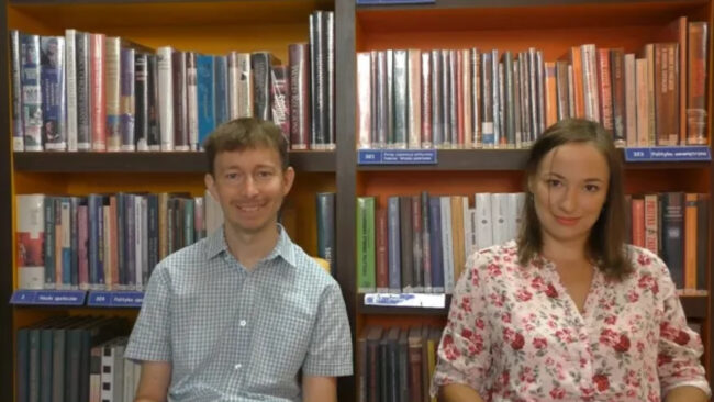 uśmiechnięci bibliotekarze na tle regału wypełnionego książkami