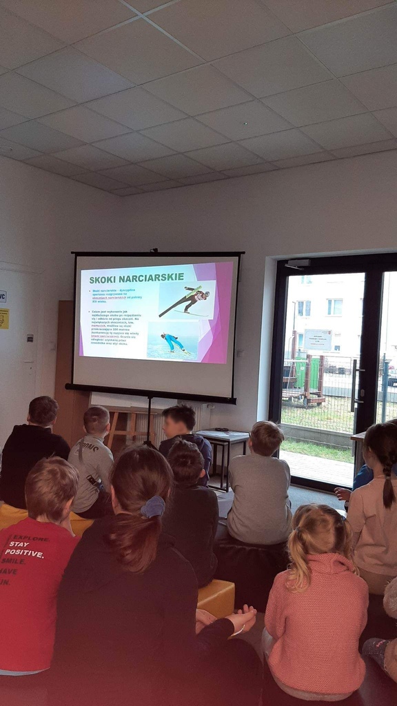 dzieci oglądają prezentację multimedialną o skokach narciarskich