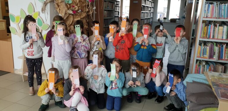 dzieci biorące udział w zajęciach bibliotecznych prezentują swoje prace plastyczne
