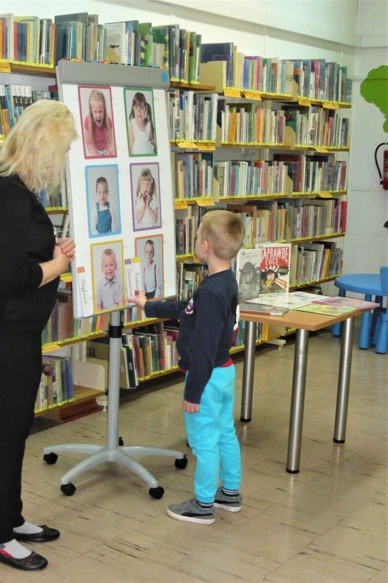chłopiec ogląda na tablicy zdjęcia emocji na twarzach dzieci