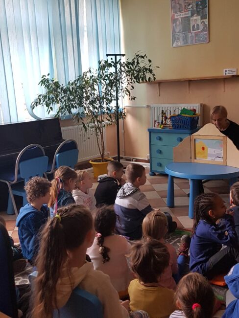 dzieci słuchają bajki w teatrzyku kamishibai
