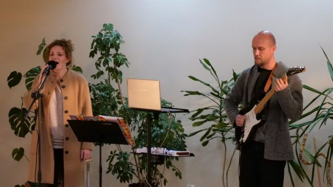 duet Pełnia występuje na scenie czytelni, w tle zieleń roślin doniczkowych