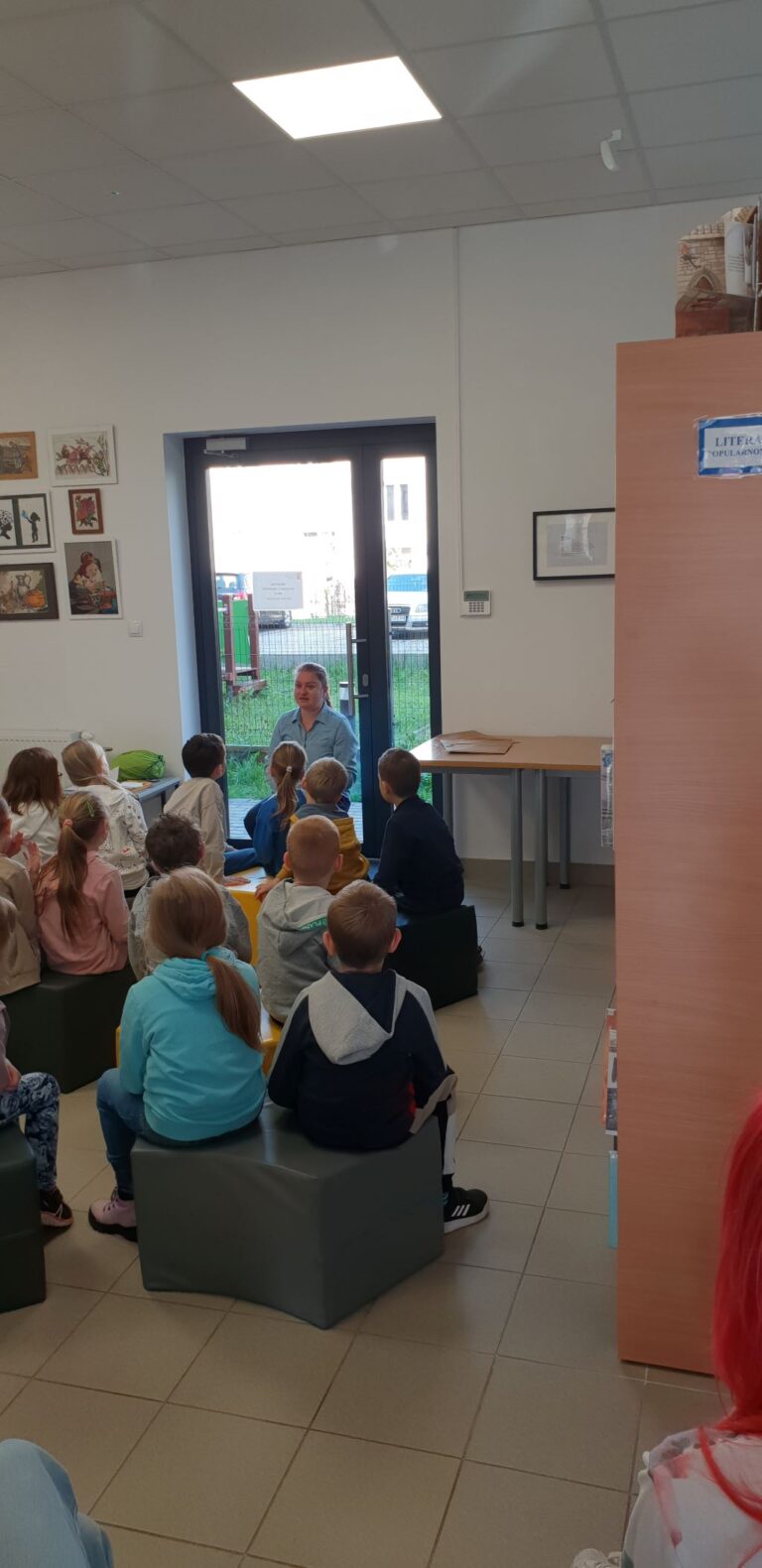 dzieci słuchają bibliotekarki opowiadającej o Irenie Sendlerowej