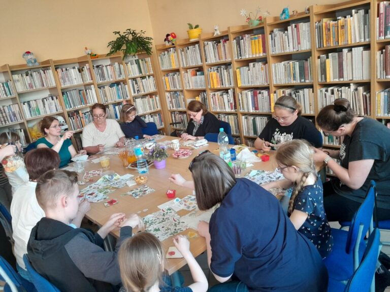 uczestnicy warsztatów w trakcie pracy twórczej przy stolikach w bibliotece