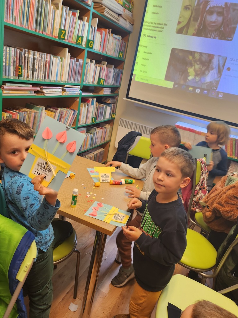 dzieci na zajęciach w bibliotece tworzą pracę plastyczną