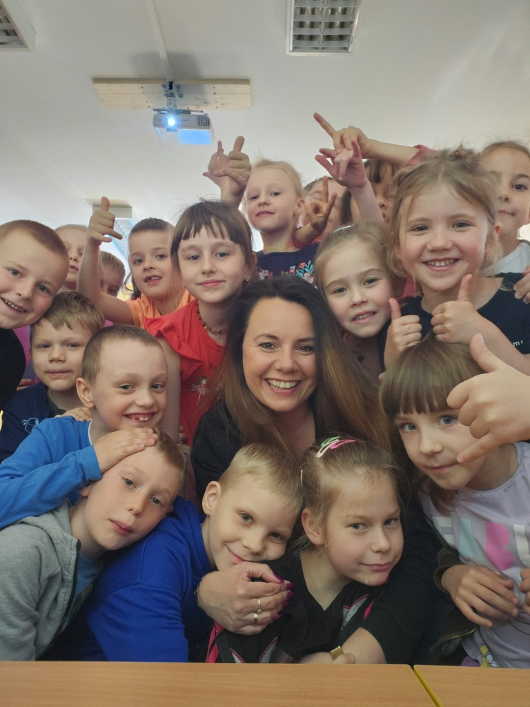 uśmiechnięta bibliotekarka pozuje do zdjęcia z dziećmi w przedszkolu
