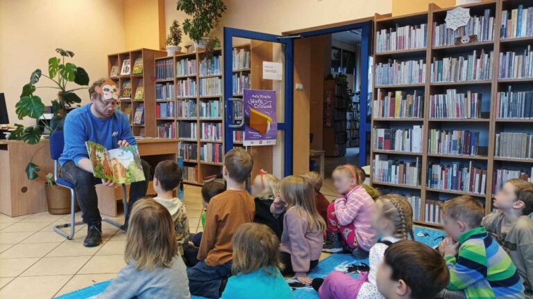 prowadzący zajęcia czyta dzieciom książkę po angielsku