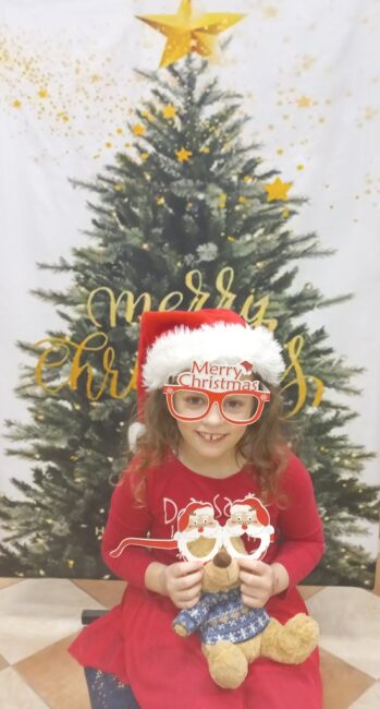 dziewczynka pozuje do zdjęcia na tle choinki,