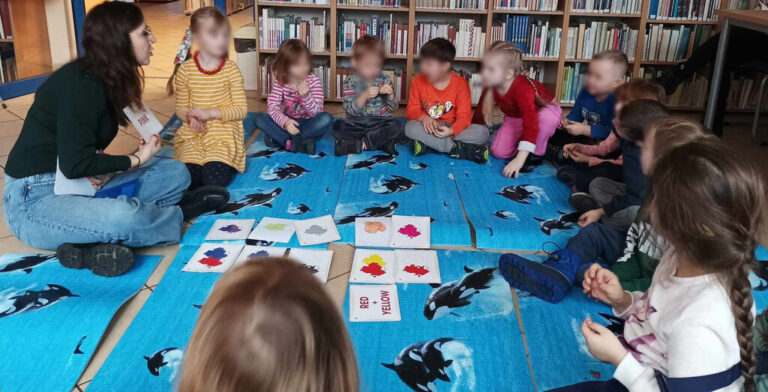 zajęcia języka angielskiego dla dzieci; dzieci siedzą na macie w bibliotece