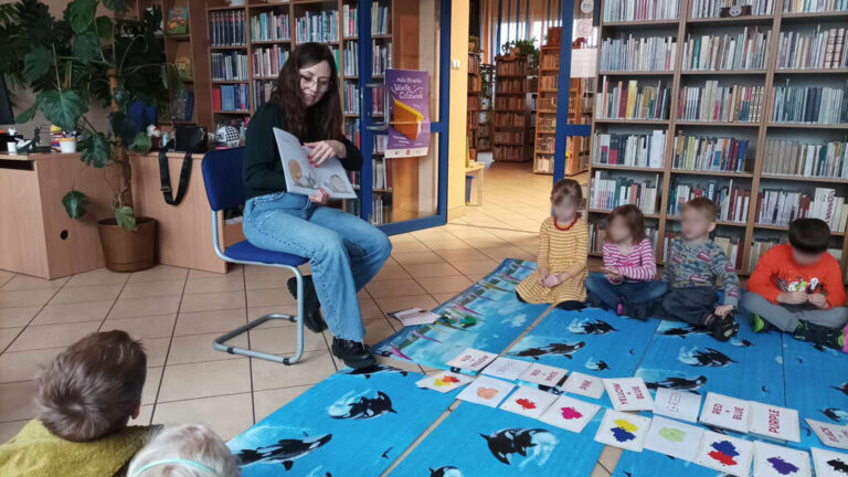 zajęcia języka angielskiego dla dzieci; dzieci siedzą na macie w bibliotece