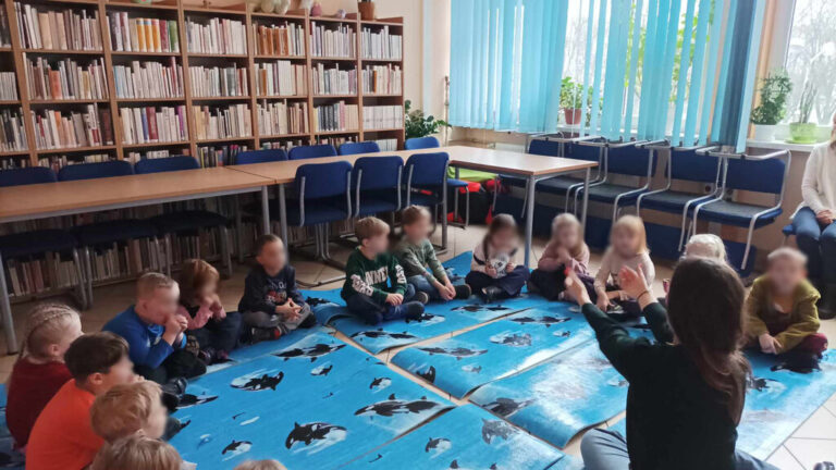 zajęcia języka angielskiego dla dzieci; dzieci siedzą na macie w bibliotece