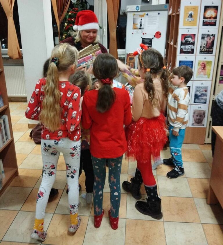 bibliotekarka w czapce mikołaja, wokół niej dzieci