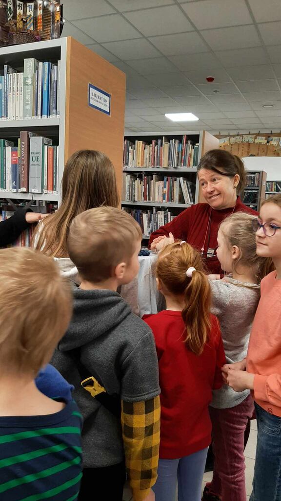grupa dzieci w bibliotece rozmawia z bibliotekarką