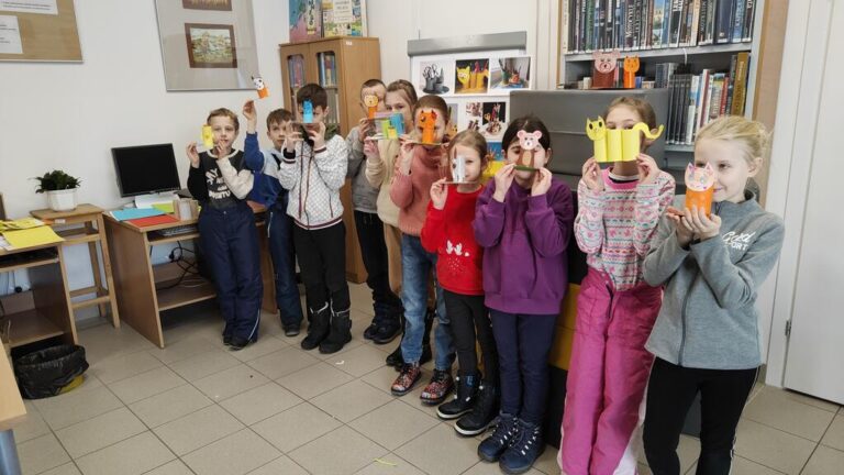 grupa dzieci w bibliotece pozuje ze swoimi pracami plastycznymi
