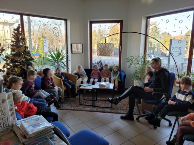 dzieci siedzą na kanapie, nauczycielka czyta książeczkę