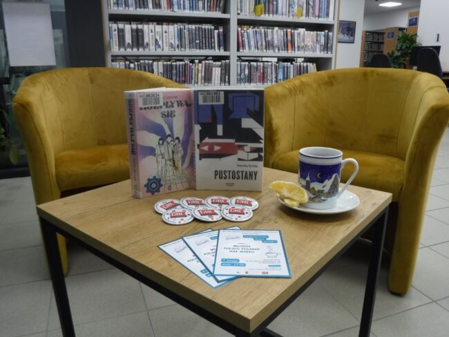 na stoliku w bibliotece stoją książki omawiane podczas spotkania, a także filiżanka kawy