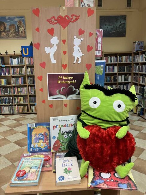 maskotka zielonego stworka i wystawka książek związanych z walentynkami