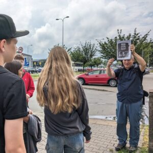 warsztaty varsavianistyczne z Krzyszfofem Gajdą; przewodnik pokazuje młodzieży archiwalne zdjęcia