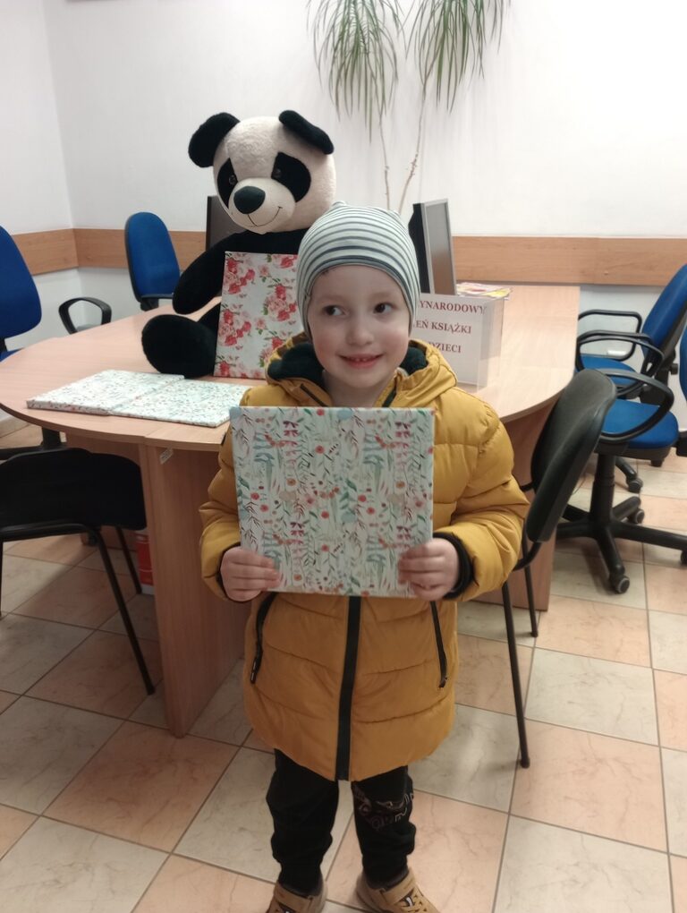 dziecko w bibliotece trzyma nagrodę niespodziankę od pań bibliotekarek