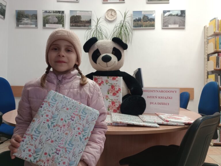 dziecko w bibliotece trzyma nagrodę niespodziankę od pań bibliotekarek