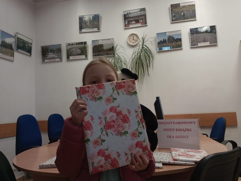 dziecko w bibliotece trzyma nagrodę niespodziankę od pań bibliotekarek