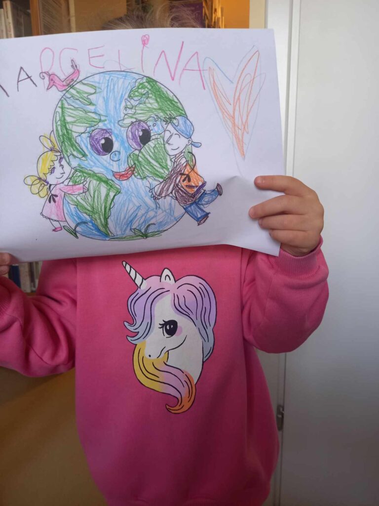 dziecko pokazuje namalowany przez siebie obrazek - pisankę