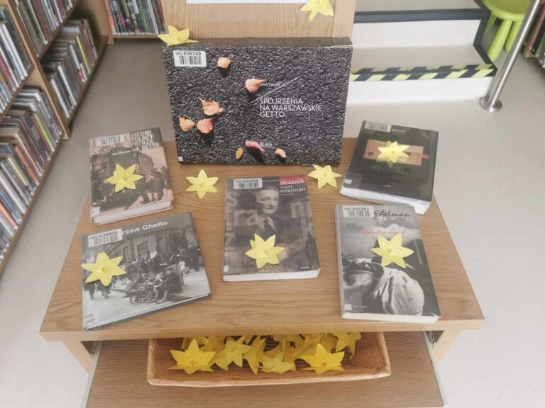 na stoliku w bibliotece są książki o powstaniu w getcie warszawskim, leżą na nich żonkile - symbole akcji